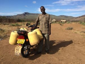 James hämtar vatten vid vår brunn till sig själv och andra i byn. Ibland har han 6 dunkar, dvs 120 liter på moppen!
